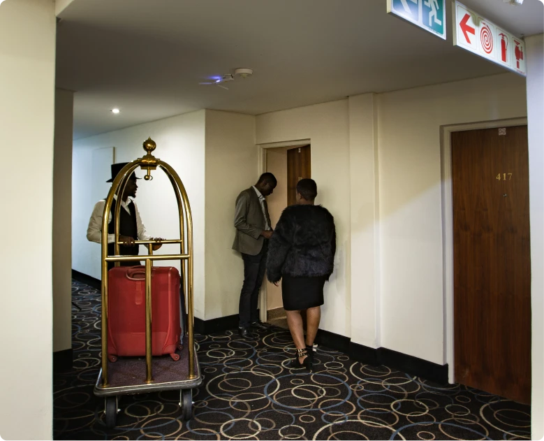 Apollo Hotel assistant showing a guest to her room and helping with her luggage